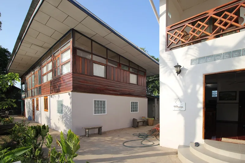 A two-story guesthouse with wooden upper walls and white ground floor on Don Det, Si Phan Don, Laos.