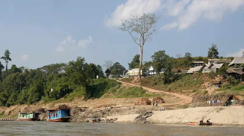 Boats moored along the riverbank at a small village with wooden houses in Xieng Kok, Laos.